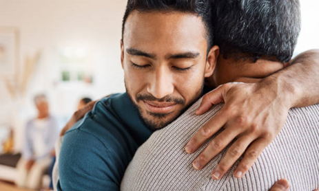 Two people embrace one another in a support group meeting.