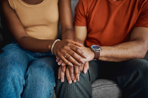 Two people sitting on a couch, one is being comforted by the other.