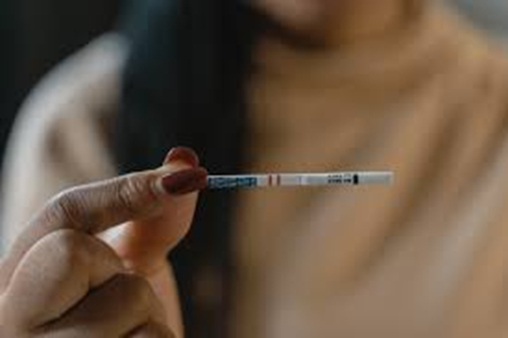 A woman holds a fentanyl test strip up.