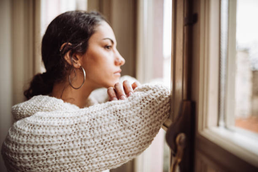 A woman looks out a window in contemplation.